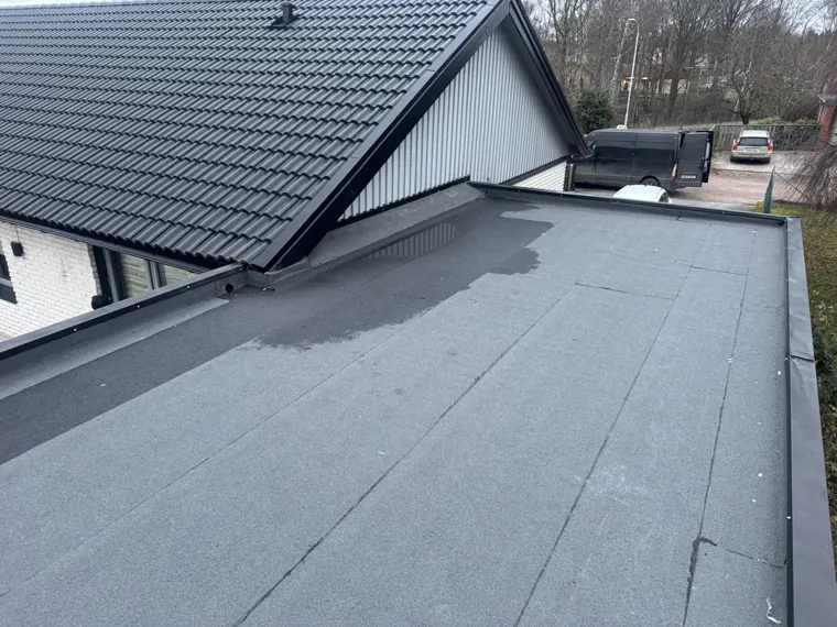 Låglutande papptak intill ett hus med takpannor